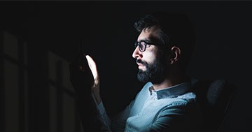 man looking at cell phone in the dark