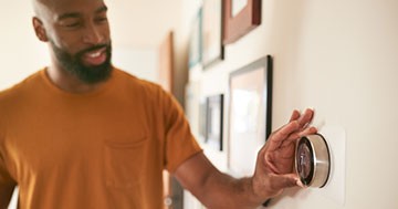 Man changing temperature on smart thermostat